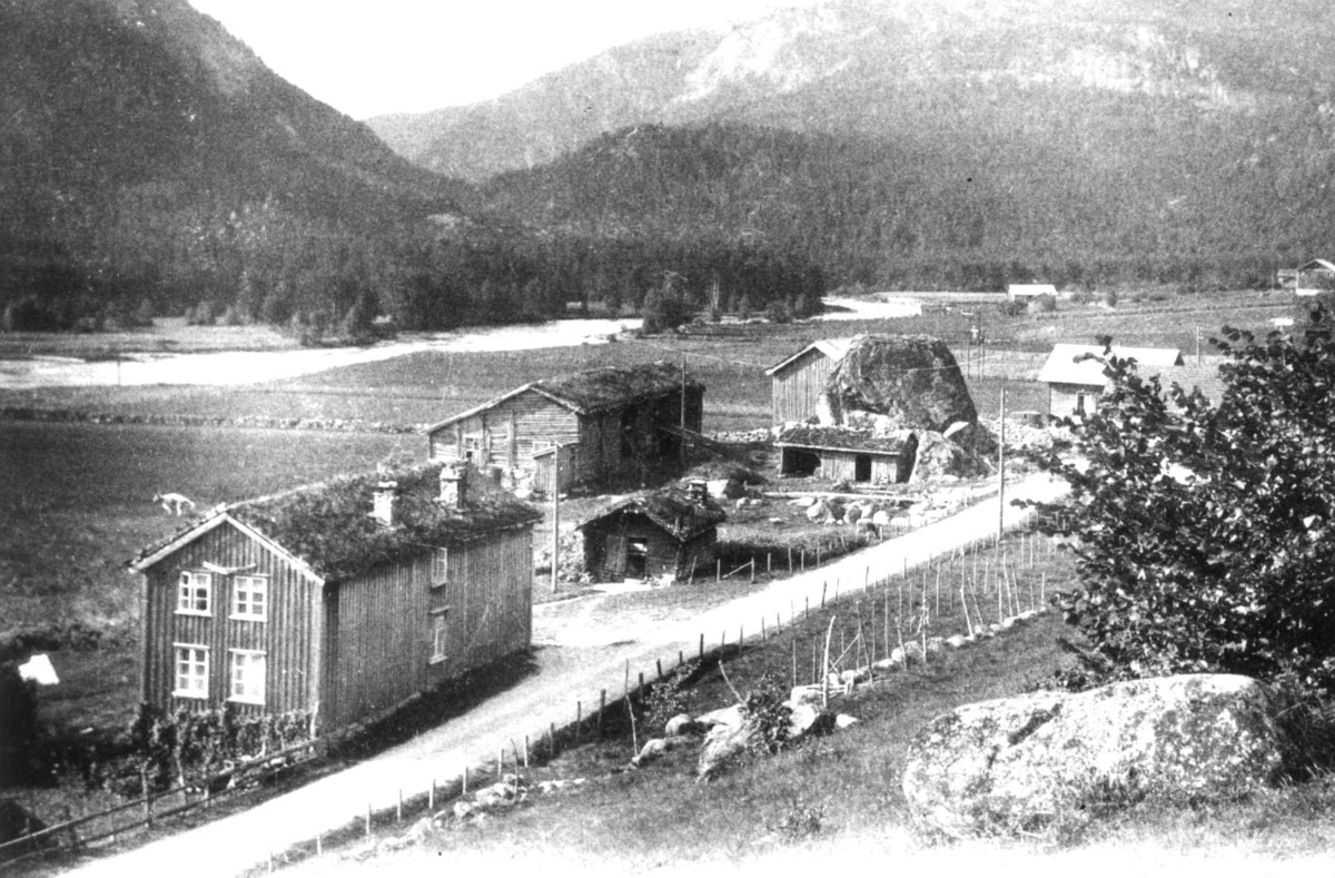 Bildet viser gården Søstog på Austenå i Tovdal.
Fra Anna Grostøls samlinger. Landskap med gårdsbruk på Tovdal, Åmli 1936.