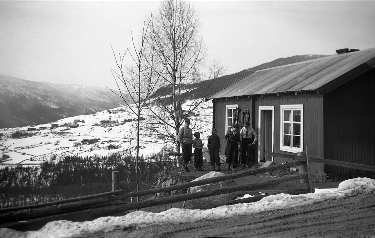 Hytte i Gol påsken 1939. To av døtrene Arentz står utenfor hytta sammen med to kvinner og en mann. Det er fortsatt snø i bygda som ses i bakgrunnen.