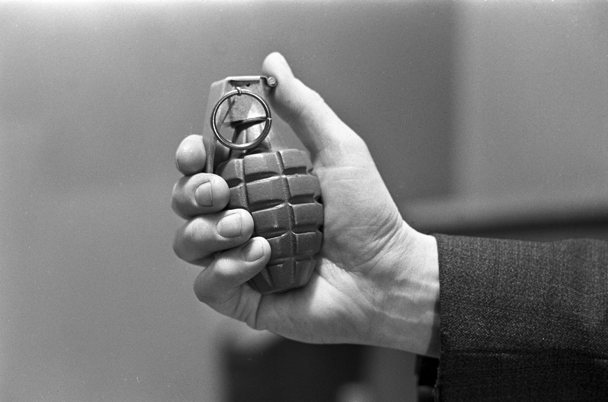 En mann holder en håndgranat. Fotografert februar 1965.
