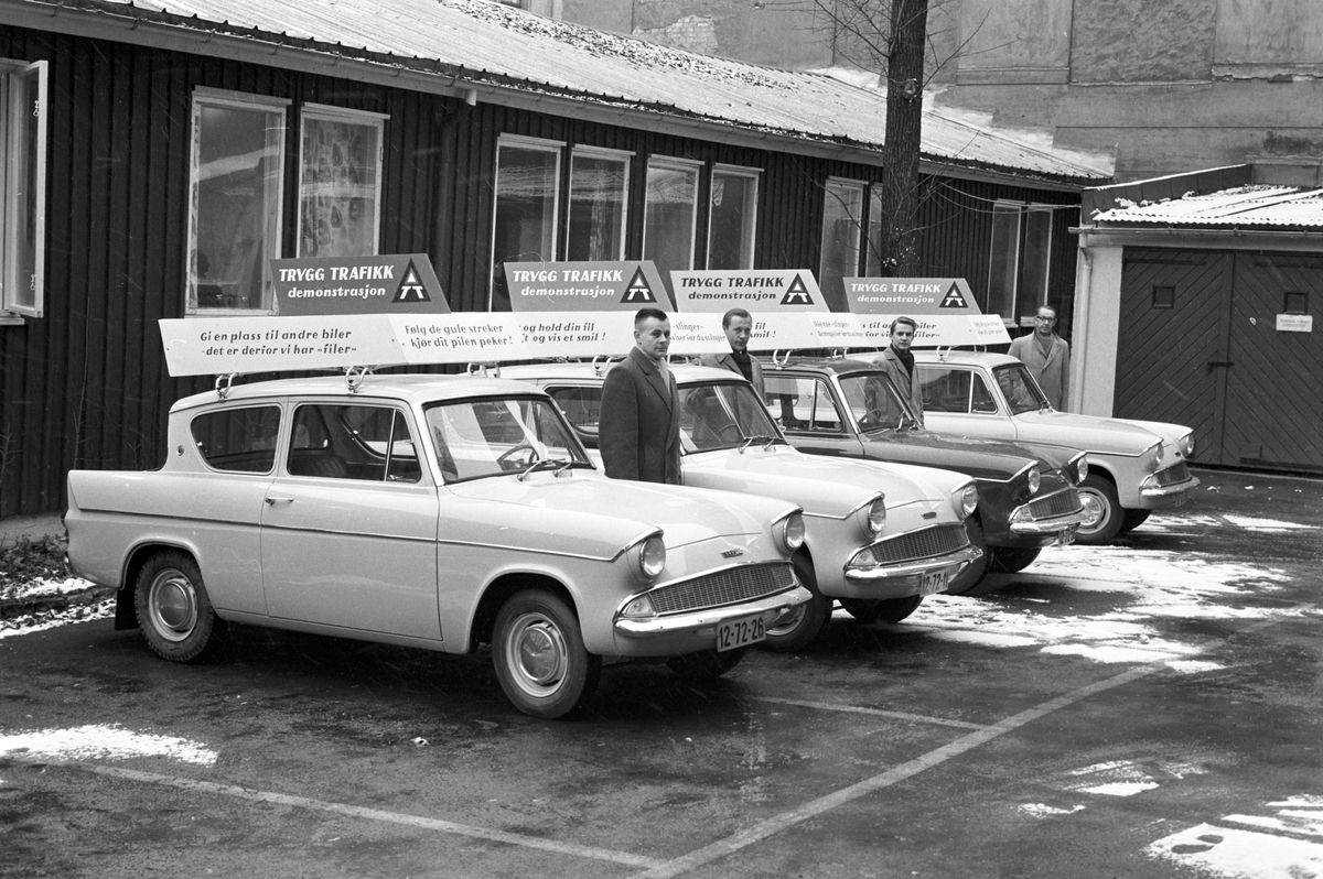 Serie. Trygg Trafikk kjører rundt med Ford Anglia, med plakater på taket. Fotografert november 1960.