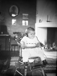 Guri Arentz sitter i en barnestol med høretelefon på. Fotogr