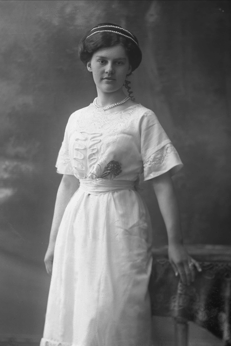 Portrett, kvinne med lys kjole og perlebånd i håret og om halsen. Frøken Constance Johansen.