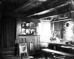 Tømmerstue, stueinteriør med langbord, hjørneskap og framska