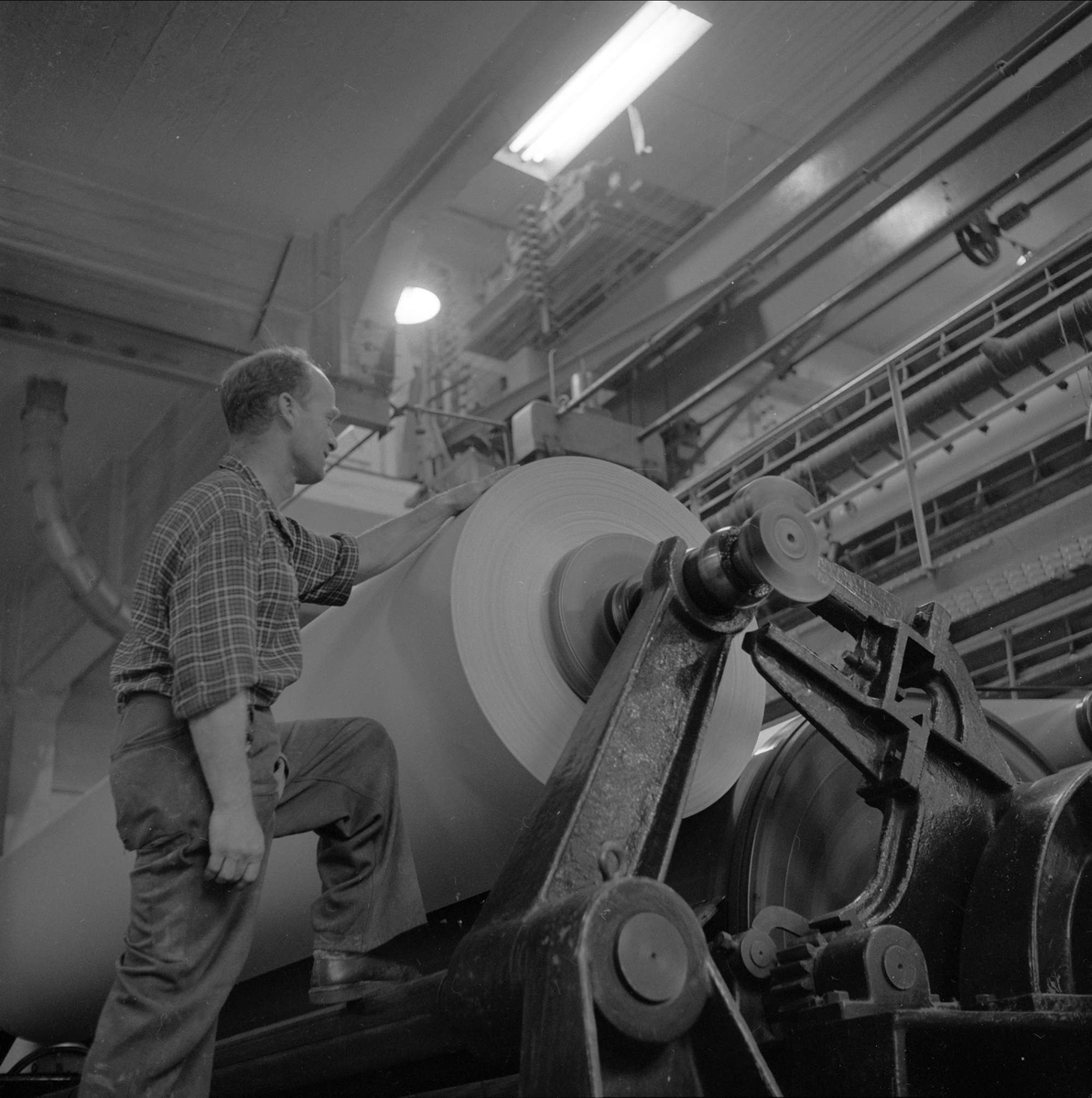 Holmen Brug i Hokksund, Øvre Eiker, Buskerud, 02.10.1958. Industriarbeider ved papirrull, produksjon av papir.