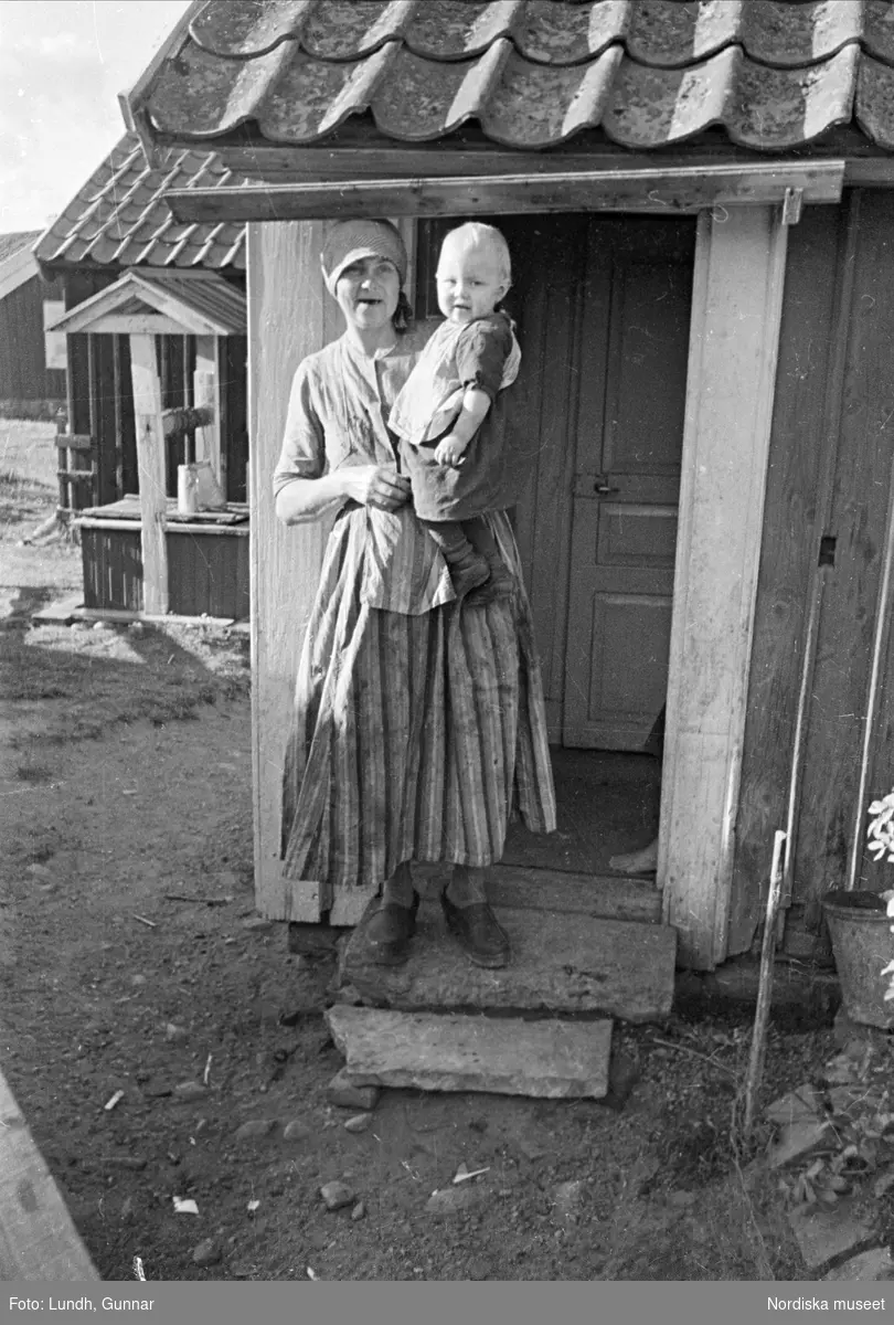 Kvinna med barn på stugtrappen.