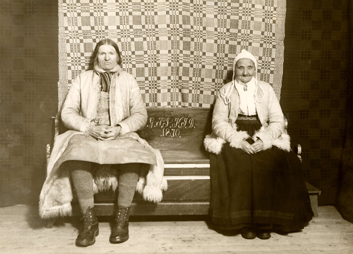 Ett äldre par sitter på en brudsoffa. Sollerön, Dalarna.