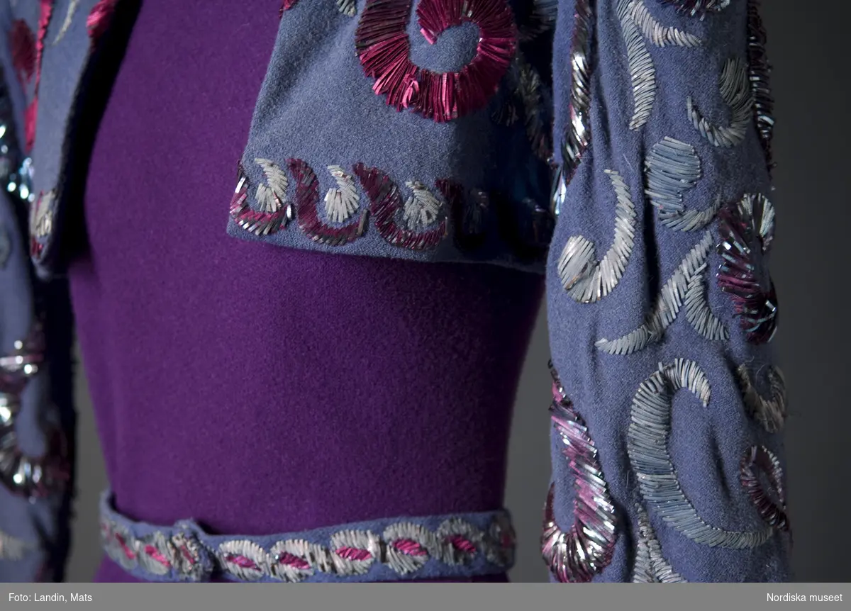 Aftonklänning av rödlila yllejersey med jacka i gråblått, rikt broderad i färger med metall-lan. Madeleine Vionnet, Paris 1938. Nordiska museet inv nr 236461.