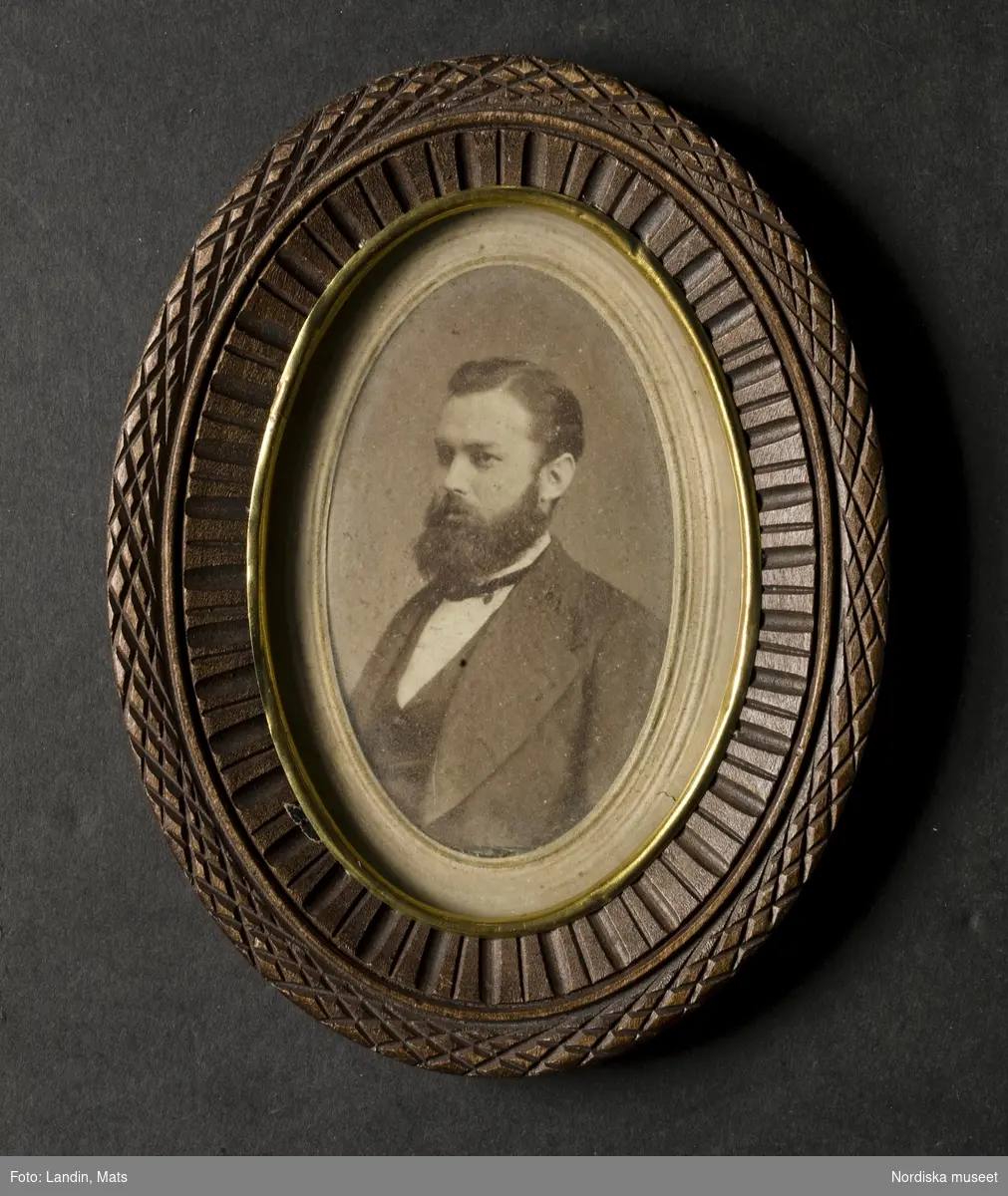 Porträtt av okänd herre med helskägg. Fotografi i oval ram av snidat trä. Nordiska museet inv.nr 194874


