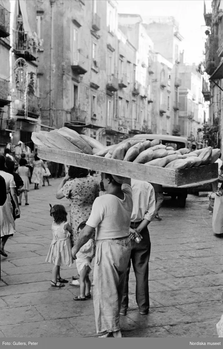 Gatuscen. Man går med en stor trälår fylld av bröd på huvudet. Neapel, Italien