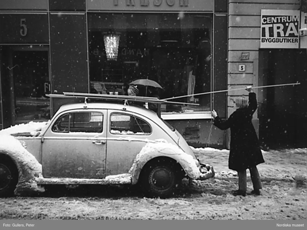 Kvinna lastar trälister på takhållare på en Volkswagen. Östermalm, Stockholm