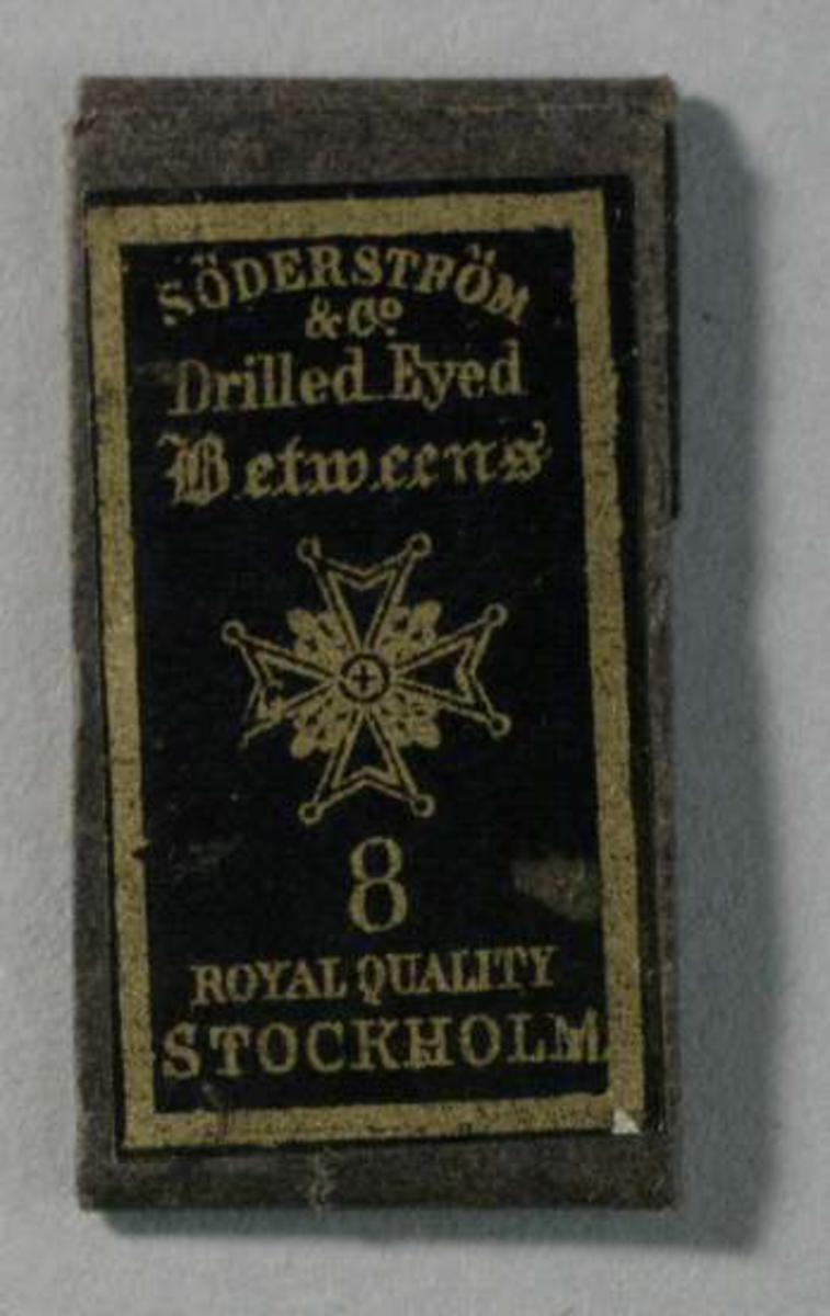 Nålbrev av svart papper med lila etikett med guldtext: Söderström & Co Drilled Eyed Betweens 8 Royal Quality Stockholm. 
Innehåller något rostiga nålar.
