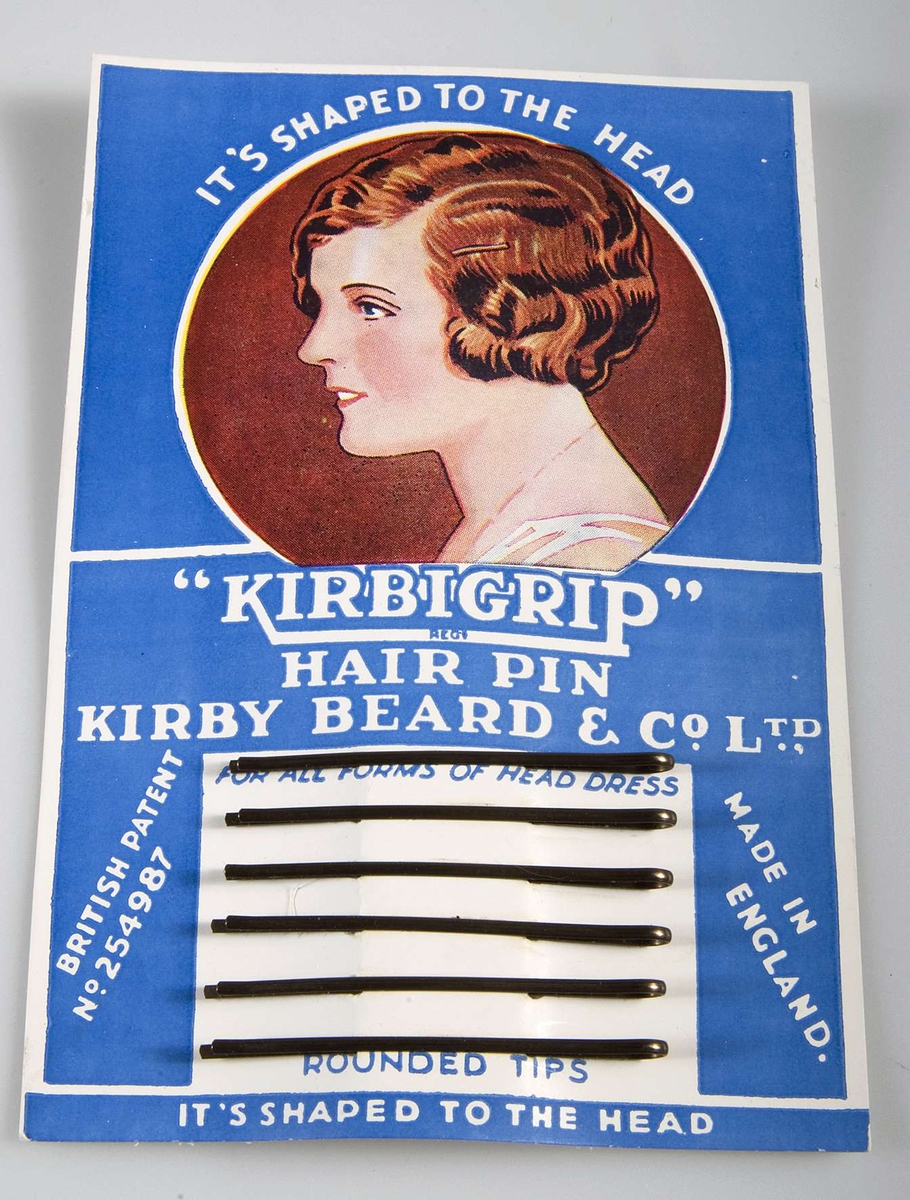 16 förpackningar med sex smala hårspännen i metall. Förpackningen består av blått papper med text i vitt och kvinnoansikte. Text: "KIRBIGRIP" HAIR PIN.

