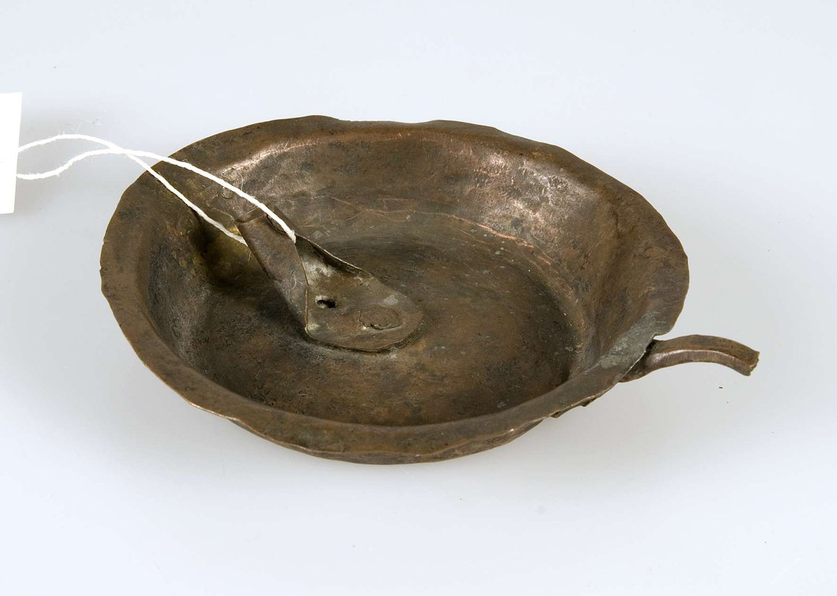 Lampa av koppar, enligt Museum Gustavianums katalog för insättande av märg och vass. Lampan har en hållare för veken samt ett litet handtag på kanten. Lampan är märkt "EC. 433. Sigtuna".