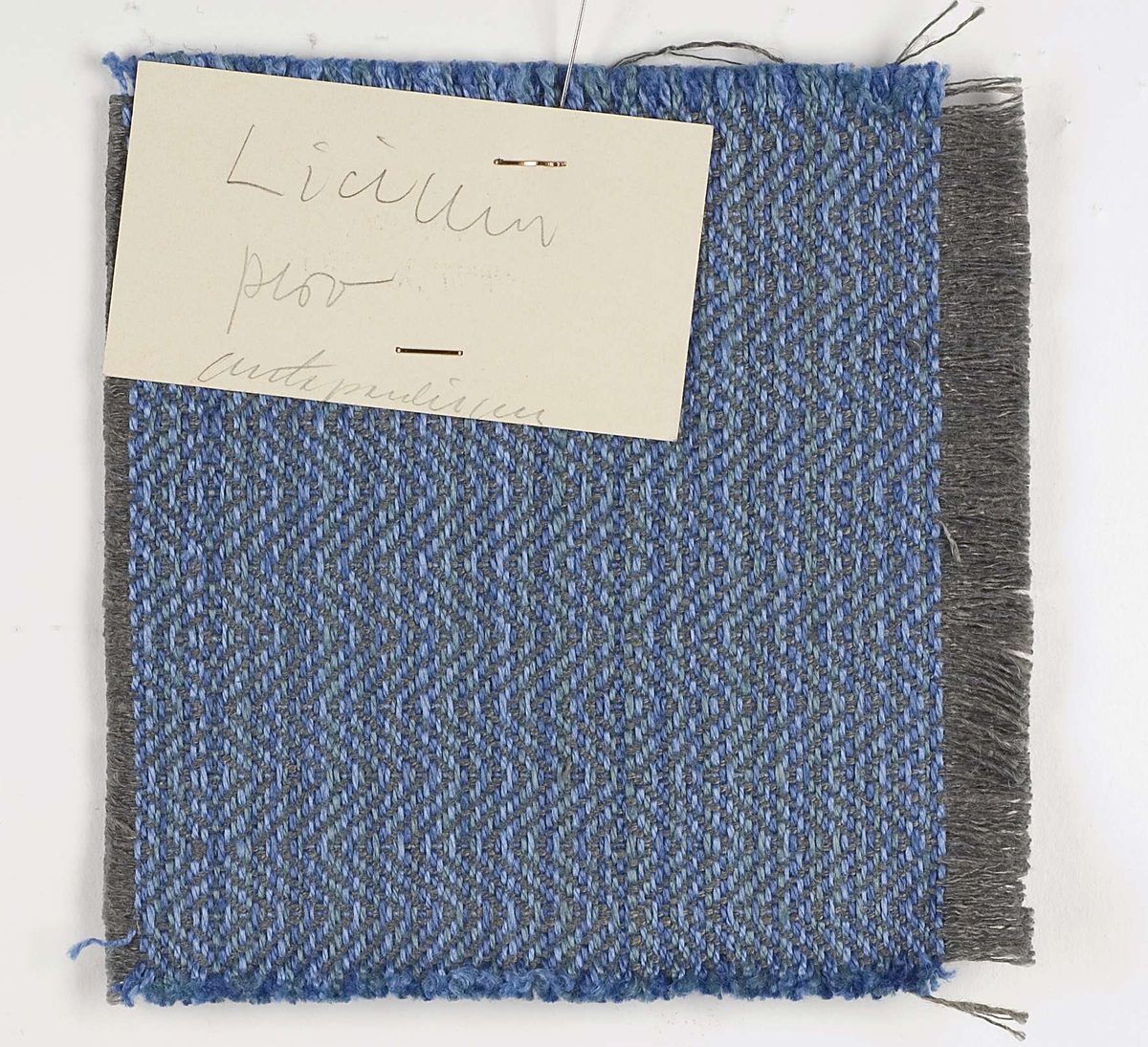Vävprov, blått, vävt i kypert av lin.
Vid vävprovet sitter en lapp med något otydlig text: "Licium prov antependium".