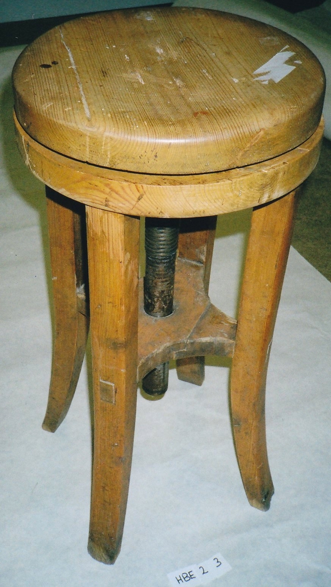 Form: Rundt sete bestående av to treskiver, den øverste kan dreies rundt for å regulere høyden, fire bein som skrår utover nederst.
