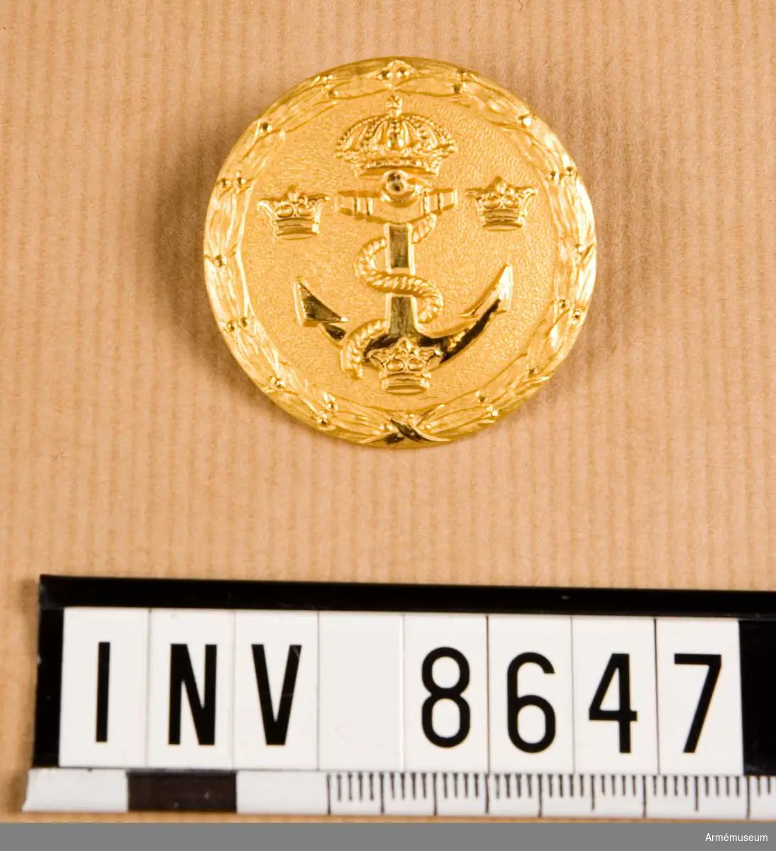 Höjd 40 mm. Bredd 40 mm. Diameter 40 mm. Vikt 16,2 g. Förgylld mässingsplatta med krönt ankare med ankartåg och tre kronor i relief på matt botten, det hela omgivet av lagerornament. På baksidan försett med fästanordning. Utföres även i vit metall. Bärs av befäl vid vaktgöring enligt vederbörande chefs bestämmande. Märket bärs på bröstets vänstra sida på liv- och ytterplagg, dock ej vid övningar i terräng.