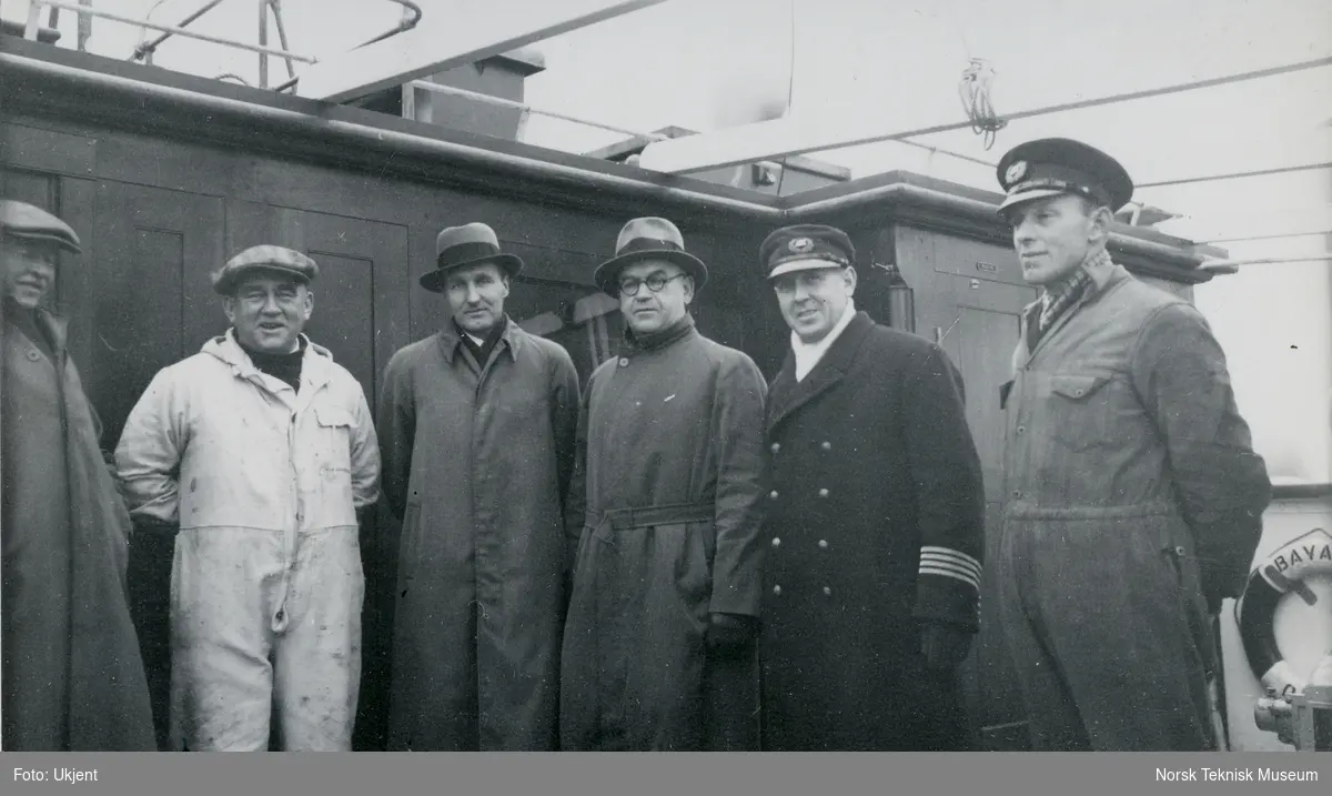 Seks menn på dekk på passasjer- og lastebåten M/S Bayard, B/N 467 under prøvetur i Oslofjorden 1. februar 1936. Skipet ble levert av Akers Mek. Verksted i 1936 til Fred. Olsen & Co, Oslo.