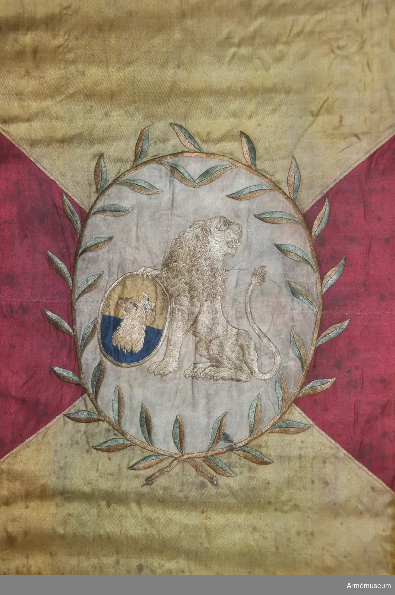 Duk av sidenkypert, fyrstyckad, gul och röd, i mitten broderat en sköld med Skånes vapen.