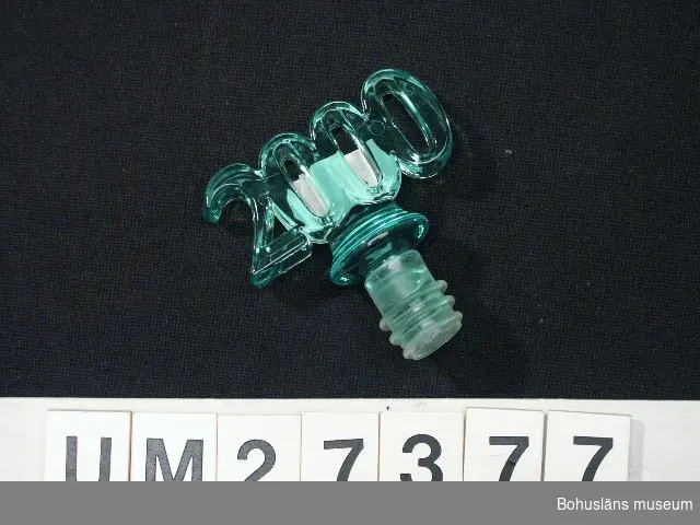 Plastkork med handtagsdel av grön genomskinlig plast formad till siffran 2000.

Inköpt  på Tiimari i Uddevalla för 24 kronor. 

För information om Millennieinsamlingen, se UM27360.