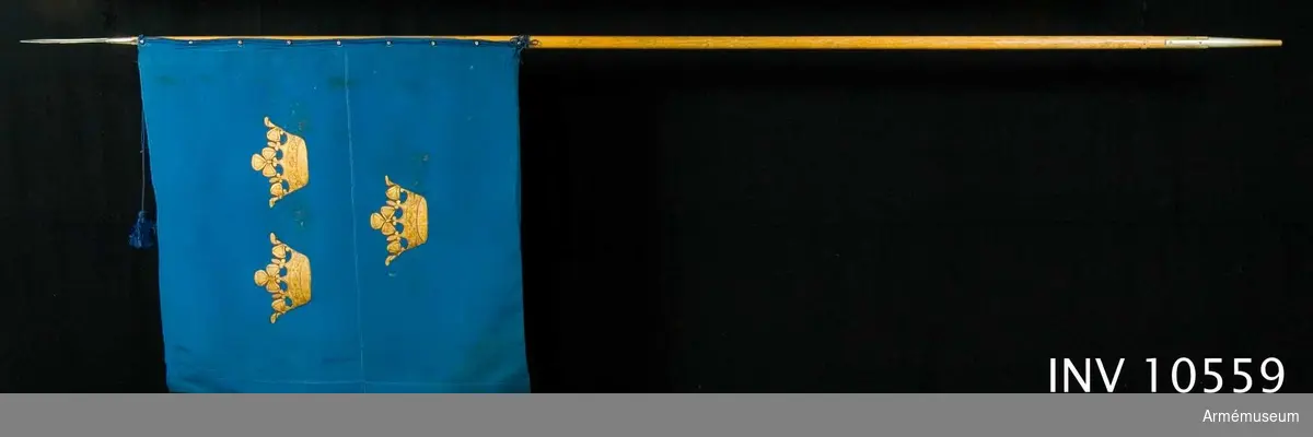 Grupp B I. 
Kommandoflagga f chefen för armén. 1920 eller 1929.
Duk av blå crepe de chine med tre målade guldkronor, placerade två och en. Sydd med en iskarvning längs hela yttersidans höjd. Fastsatt vid den bruna stången med en blå silkesnodd, trädd genom hålförsedda knoppar, 9 st. Spetsen är formad som en bajonett. Till den finns lädertuta.
