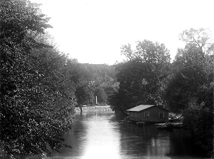 Enligt senare noteringar: "Bäveån i Uddevalla, vid Hasselbacken från "träbron". 
I bakgrunden "Roskildestenen". Th. bryggor och tvätthus."