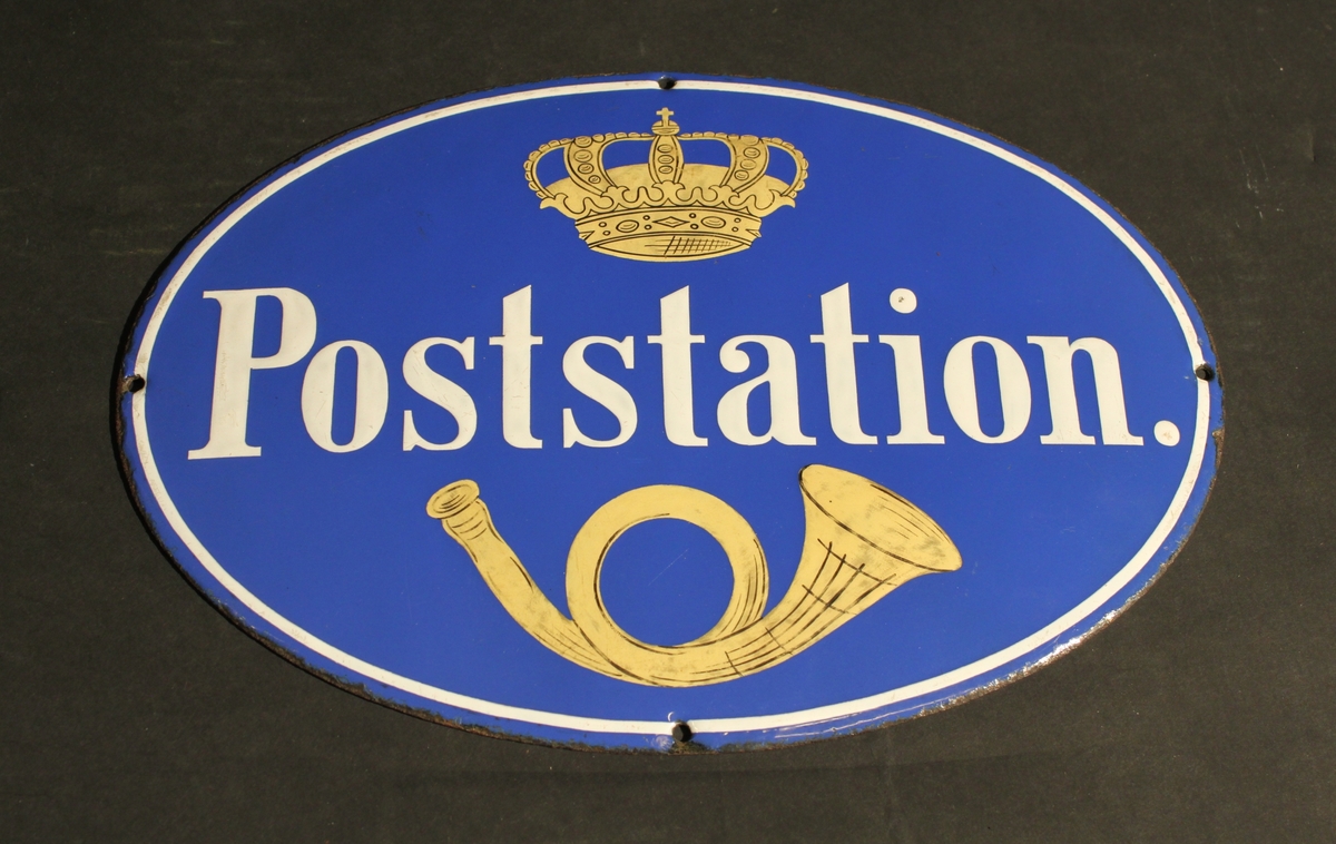 Poststationsskylt, oval, i emaljerad järnplåt, med vit text
mot blå bakgrund. Över texten en krona i rött och gult, under texten
ett gult posthorn. Längs kanten löper en vit rand. Användes på
poststationer, modellen antogs 1892-06-13. Fyra hål för upphängning.