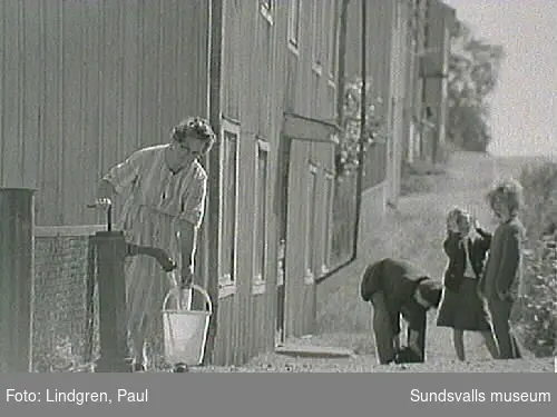 Kvinna hämtar vatten vid gårdspumpen på Bleckslagaregatan 34. Det närmaste huset revs under 1960-talets början.