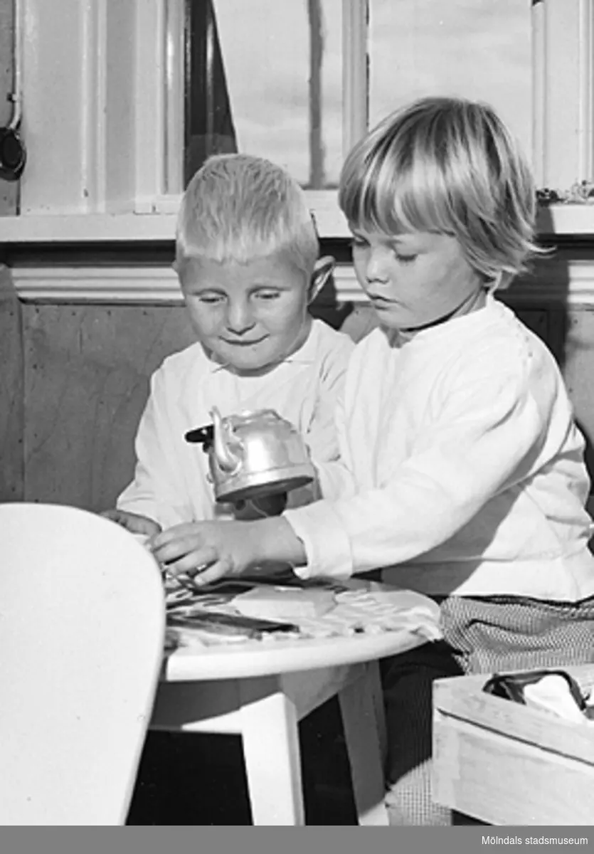 En pojke och en flicka sitter vid ett "kaffebord". Holtermanska daghemmet 1953.
