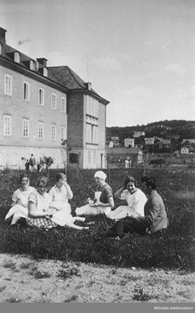 Bilden är tagen på södra sidan av Mölndals lasaretts gamla byggnad. I  bakgrunden ses stadsdelen Trädgården. Damerna på bilden är okända.
