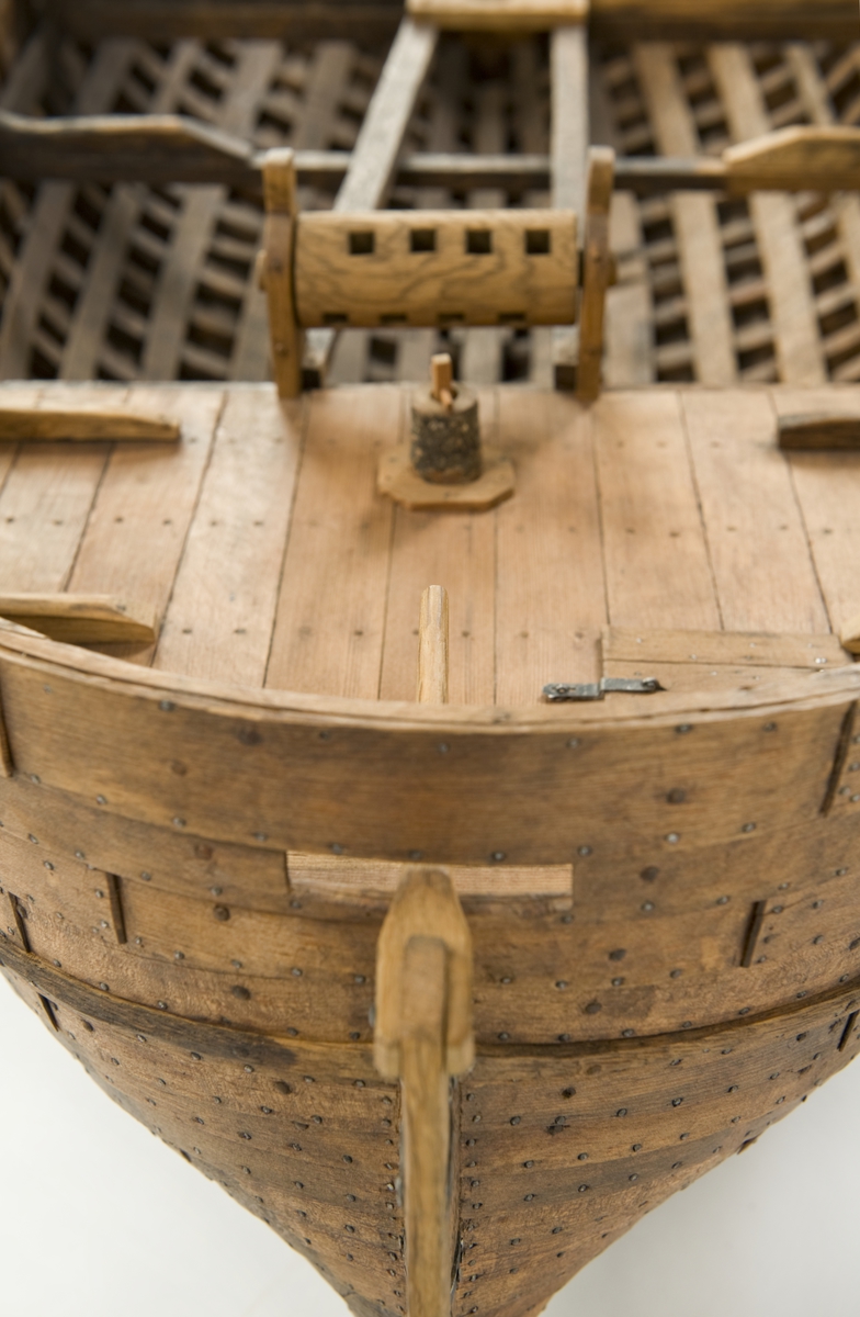 Fartygsmodell. Lastskuta från 1500-talet, klinkbyggd med sjutton bord på var sida, odäckad med back och akterdäck. Skrovet betsat ljust och mörkt. Pump och roder, röstjärn av trä, ankare och riggad mast.