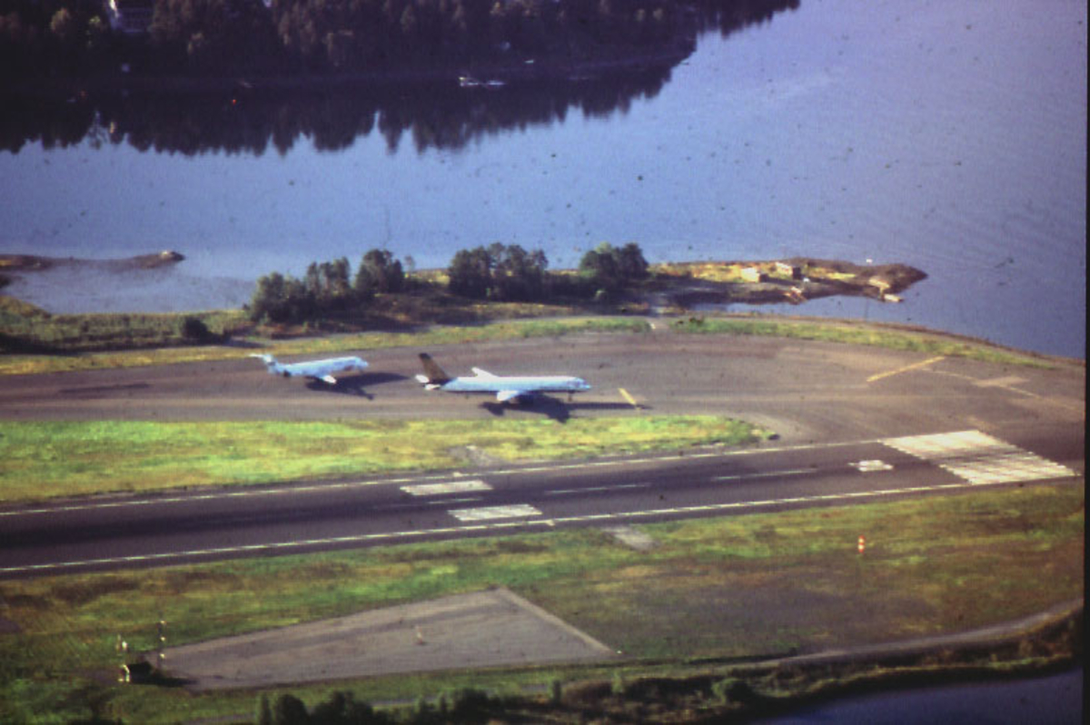 Lufthavn, flyfoto over lufthavnområdet.  2 fly på vei mot enden av rullebanen.
