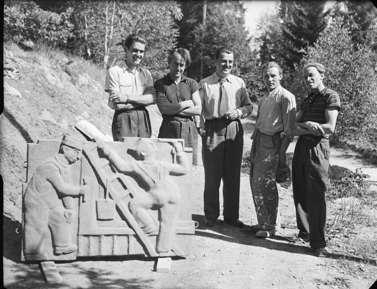 Grupporträtt med fem män kring William Marklunds relief med målare