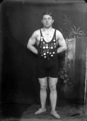 Studioportrett i helfigur av en tatovert mann med mange meda