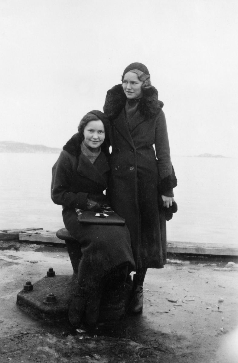To unge kvinner fotografert på kai i sentrum, Trondenes og Måga i bakgrunnen.