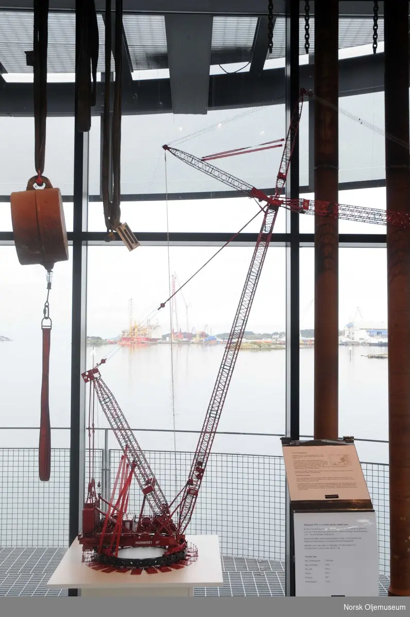 En modell av verdens største mobile krane - Mammoet PTC - står utstilt på Norsk Oljemuseum i en periode mens originalkranen er i arbeid på Yme-plattformen, som ferdigstilles ved Bergen Group Rosenberg Verft i Stavanger (i bildets bakgrunn). 