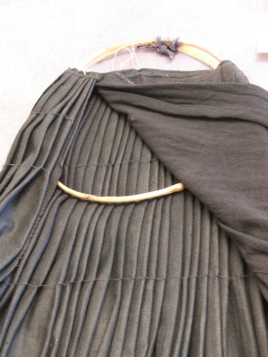 På vranga er det sydd kanting med 7,5 cm.bomullsstoff . Stoffet har loddrette striper i brunt, grønt, svart, raudt, blått.På ein del nedst: svart fløyelskant.