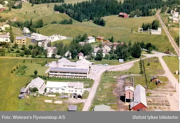 Skråfoto av Rakkestad Eggsentral, "Eggsentralen" på folkemunnne - idag; Prior Norge, 
13. juli 1964.
Villastrøk og Trafostasjon i bakgrunnen.  Rakkestad sag og høvleri til høyre.