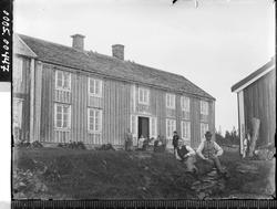 Våningshus med noen mennesker i forgrunnen.