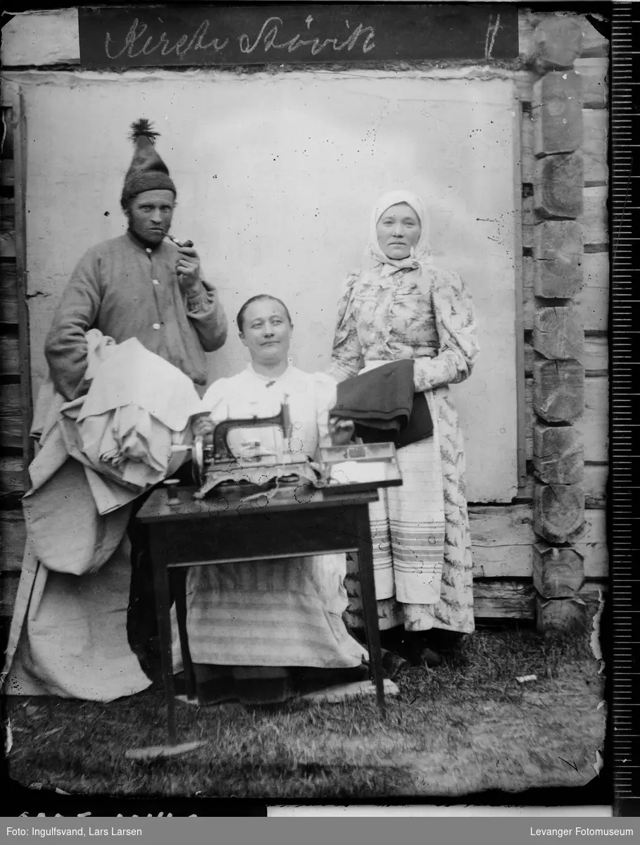 Gruppebilde av en mann og to kvinner ved en symaskin.
