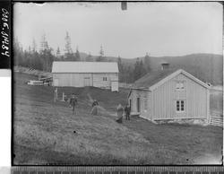 Gårdsbygninger med to kvinner og to menn ved siden av.