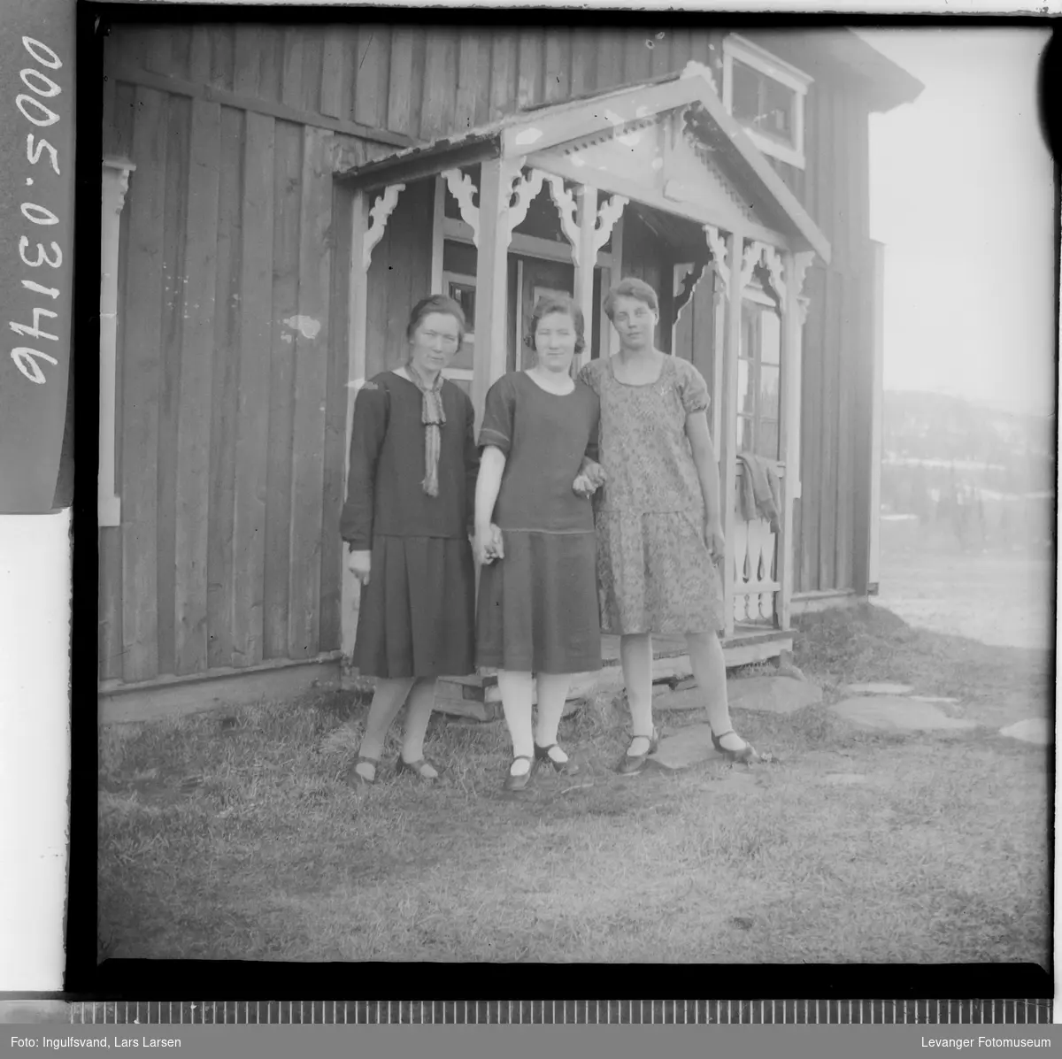 Gruppebilde av tre kvinner ved en bygning.