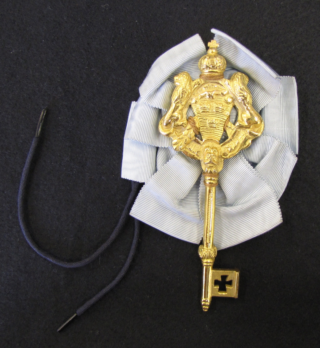 Nyckel tillhörande kammarherreuniformen. Nyckeln är förgylld med tre kronor flankerad med två lejon. Nyckeln är krönt och fästad på ett serafimerblått sidenband. 

Kammarherren har som uppgift att tjänstgöra i kungens omedelbara närhet. När kammarherren är i tjänst bär han en nyckel som ämbetstecken. Nyckeln fästes bak på uniformen vid ryggslutet. Nyckeln symboliserar att kammarherrarna historiskt har haft tillträde till den kungliga personens privata rum.

Erik T:son Uggla var protokollsekreterare vid Vattendomstolen i Vänersborg samt auditör (juridisk granskare av militärrättsskipning).
Erik var kurator vid Västgöta Nation i Lund. Genealog och heraldiker. Innehade en omfattande samling av exlibris vilken donerats till Riddarhuset. Samlingen hade påbörjats av Eriks far.

Erik var mycket intresserad av ordensväsende samt var redaktör för Ordenskalenders samt Ointroducerad Adels kalender. Han var hedersledarmot av Västra Sveriges Genealogiska förening. Kammarjunkare 1953, Kammarherre 1959.