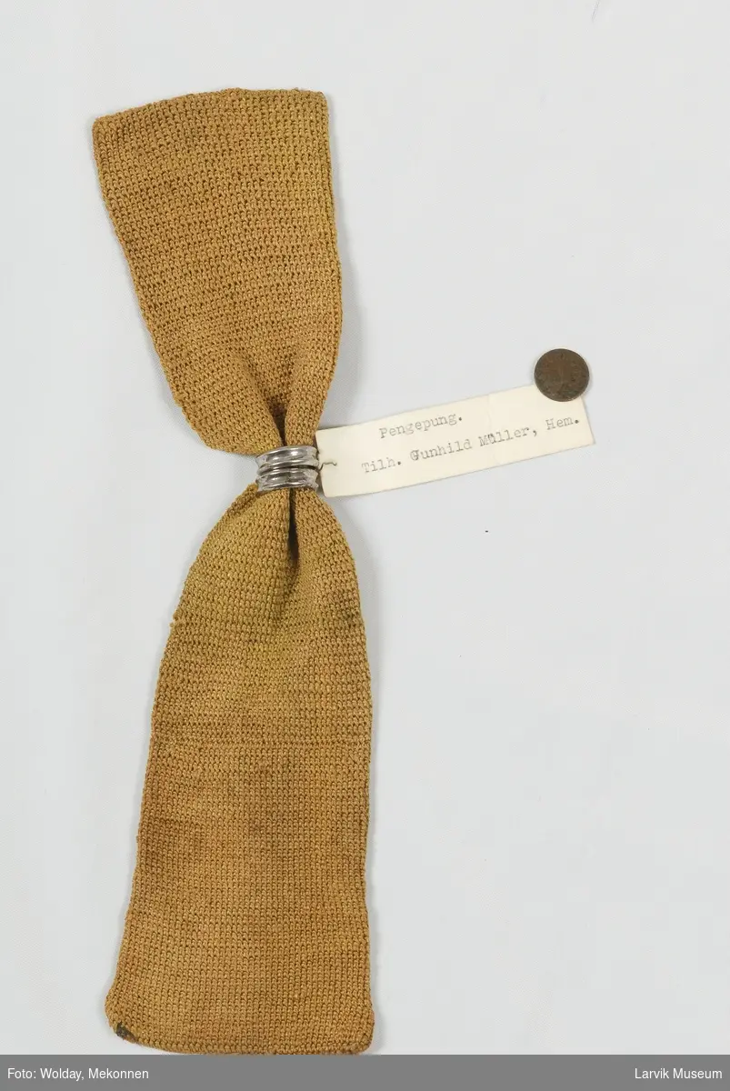 Heklet av gulgrønt silkegarn(?) i faste masker 2 sølvmetallringer, inneholder: 1 rusten knapp og 1 ettøring fra 1878
