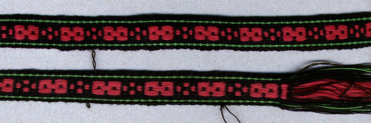 Band vävt i varprips med plockat mönster. Svart botten, rosarött mönster i mittpartiet, en smal grön rand längs vardera sidan. Ofållat/avklippt i var ände. Varp i svart, rosarött och grönt 2-trådigt s-tvinnat bomullsgarn nr 30/2.Inslag i svart 2-trådigt s-tvinnat bomullsgarn nr 30/2, två trådar tillsammans. Bandet/material och mönster till bandet har saluförts på Hemslöjden som häradsband för Harjagers dräkt.