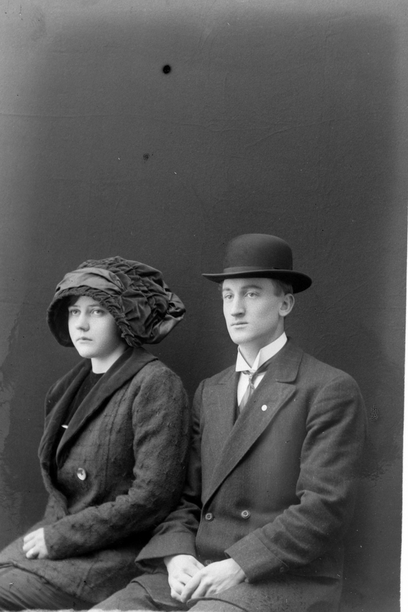 Studioportrett av kvinne med spesiell hatt og mann med bowlerhatt.