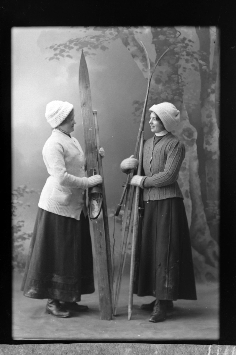 Studioportrett av to turkledde kvinner med ski.