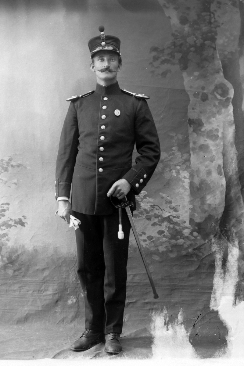 Studioportrett av en mann i uniform med sabel.
