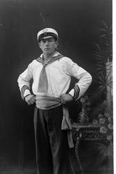 Studioportrett av en mann i spesiell drakt, med skjerf knytt