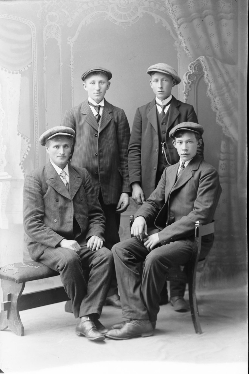 Studioportrett av fire unge menn i helfigur.