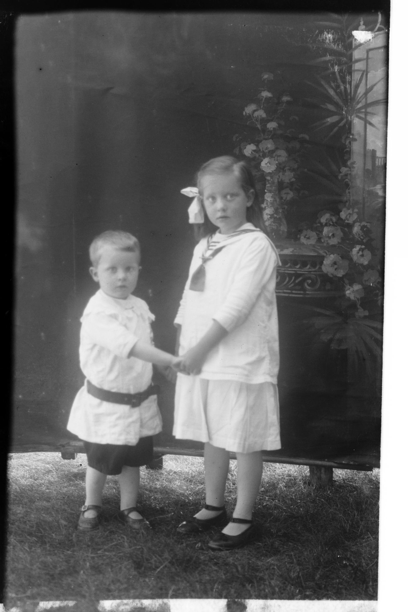 Studioportrett av to barn i lyse klær.